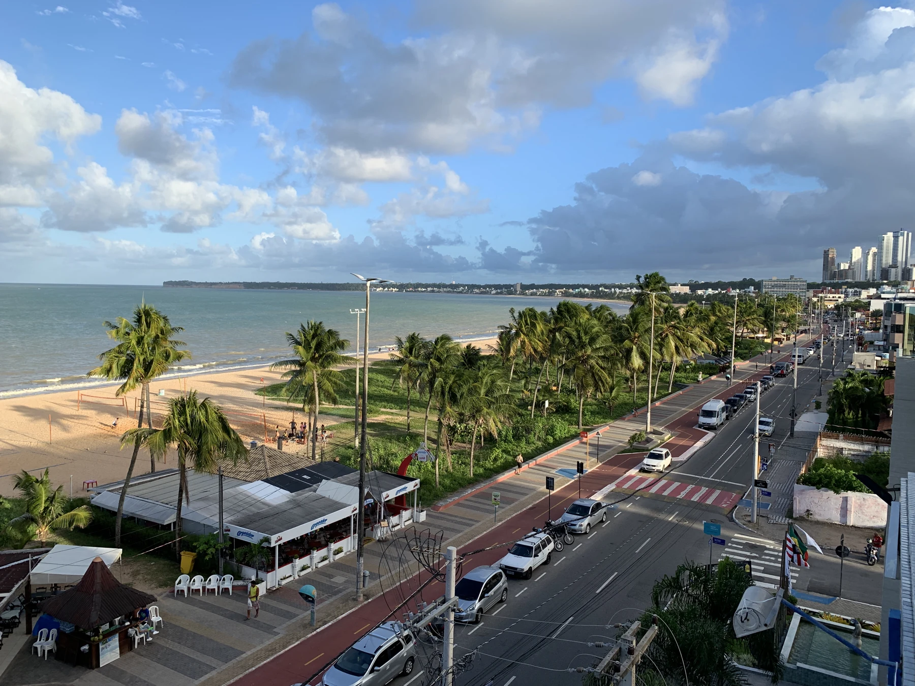 Vista da orla de Tambaú e Cabo Branco em João Pessoa, com faixa de areia, palmeiras e prédios